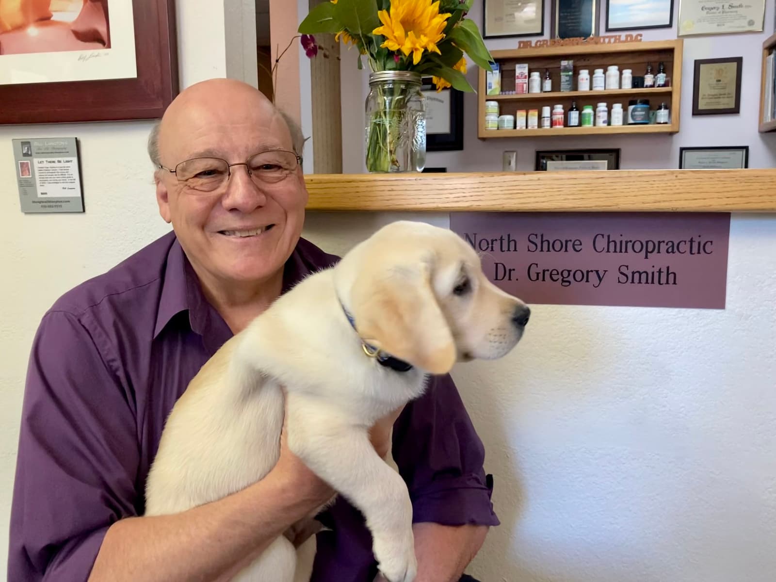 Dr. Gregory Smith of North Shore Chiropractic holding a puppy in the clinic