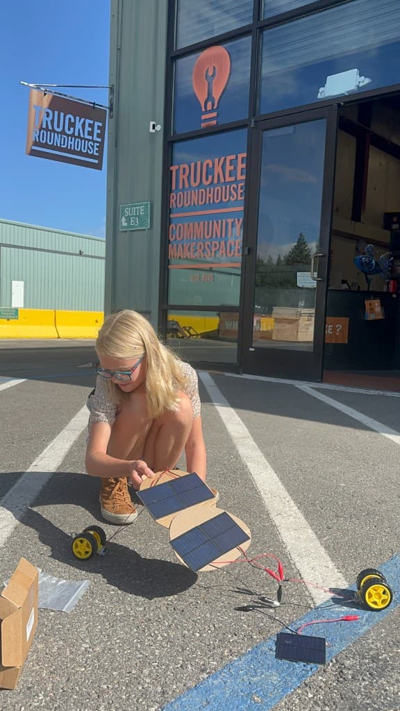 Camper assembling cardboard solar cars in the parking lot outside Truckee Roundhouse